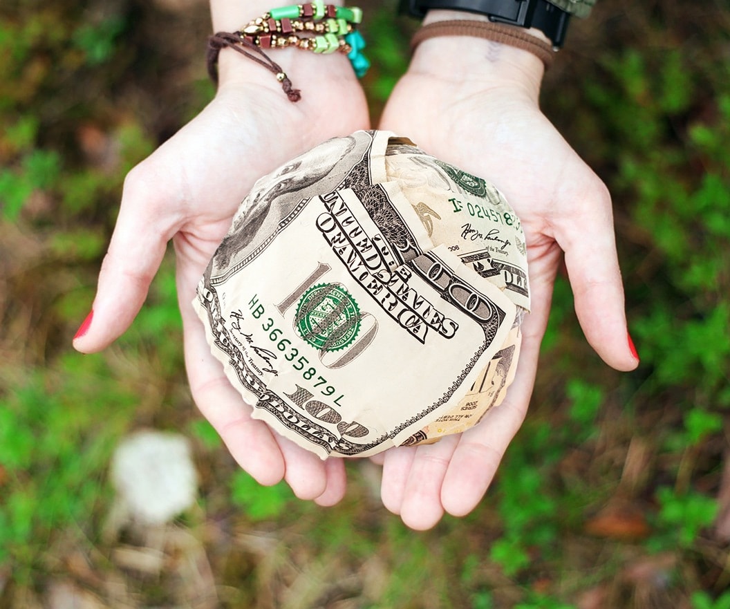 Climbing the kilimanjaro for charity — hands holding a ball of money depicting charity donations.