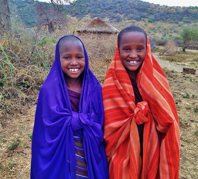 Wildlife safari adventures — two children smiling in maasai village, kenya.