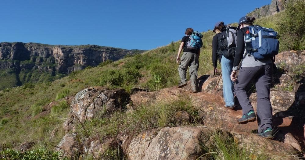 Hiking boots review — three hikers trekking on a trail in the mountains.